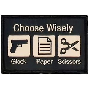 May include: Black patch with white text that reads "Choose Wisely".  Three white squares with black icons: a gun, a piece of paper, and scissors.  The text below the squares reads "Glock, Paper, Scissors".