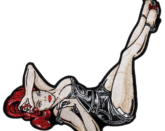 May include: Embroidered iron-on patch featuring a pin-up girl with red hair, wearing a black jumpsuit and red heels.