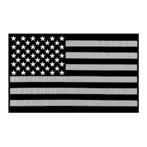 May include: A black and white American flag patch with a reflective finish. The stars and stripes are white on a black background.
