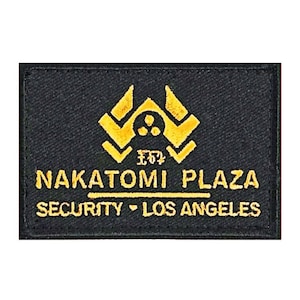 May include: Black embroidered patch with a gold logo of a stylized building with the text "NAKATOMI PLAZA SECURITY - LOS ANGELES"