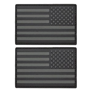 May include: Two black and gray American flag patches. The patches are made of a textured material and have a stitched border.