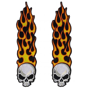May include: Two identical embroidered patches, each featuring a white skull at the base with black eye sockets and teeth, topped with a tall, vertical design of stylized orange and yellow flames outlined in black against a black background.