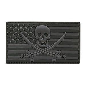 May include: Black and gray embroidered patch with a skull and crossbones design. The skull is wearing a bandana and the crossbones are swords. The patch is in the shape of the American flag.