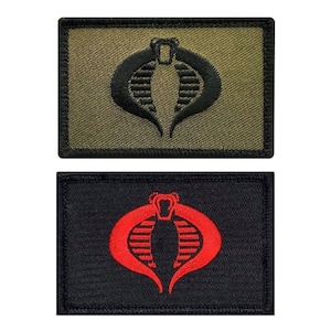 May include: Two embroidered patches featuring the Cobra symbol from the G.I. Joe franchise. One patch is black on a green background, and the other is red on a black background.