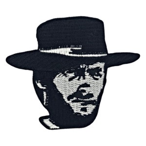 May include: Black and white embroidered patch of a man's face with a cowboy hat. The man has a mustache and beard.