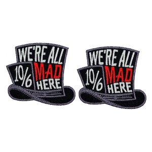 May include: Two black and white embroidered iron-on patches shaped like top hats. The patches feature the text "We're All 10/6 Mad Here" in white and red lettering.