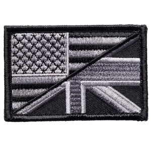 May include: A rectangular embroidered patch featuring a split design. The top left section displays the stars and stripes of the American flag, while the bottom right section shows the Union Jack of the British flag, both in shades of gray and black.