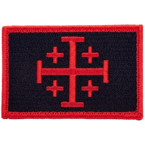 May include: A rectangular embroidered patch featuring a black background with a red Jerusalem cross centered in the middle. The patch is finished with a thick red stitched border that frames the entire rectangular shape of the fabric piece.