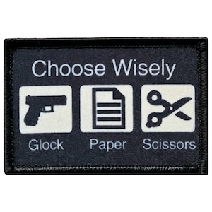 May include: Black rectangular patch with the text "Choose Wisely" above three white icons: a pistol labeled "Glock", a paper icon labeled "Paper", and scissors labeled "Scissors".