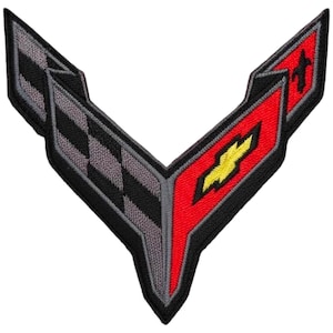 May include: Embroidered patch featuring a stylized V-shaped design. The patch incorporates a checkered flag pattern in black and gray, a red section with a yellow emblem, and a black border. The patch is likely for automotive enthusiasts.