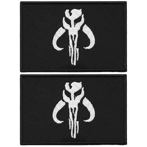 May include: Two black rectangular patches with a white Mandalorian skull emblem. The emblem features a stylized skull with curved horns and vertical lines. The patches are likely for clothing or accessories.