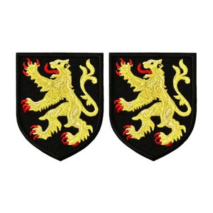 May include: Two embroidered patches featuring a golden lion rampant on a black shield. The lion has red claws and tongue. The patches are likely for clothing or accessories.