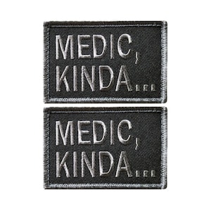 May include: Two black embroidered patches with white stitching. The text on the patches reads "Medic, Kinda..."