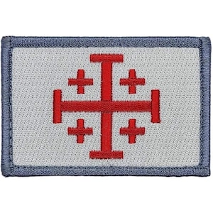 May include: A white patch with a red cross with four smaller crosses on each arm. The patch has a blue border.