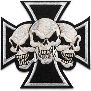May include: Embroidered patch featuring three skulls centered on a black and white cross design. The skulls are off-white with detailed teeth and eye sockets, set against a black fabric background with white stitching.