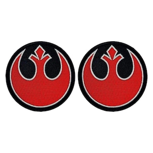 May include: Two red, white, and black embroidered iron-on patches featuring the Rebel Alliance symbol from Star Wars.