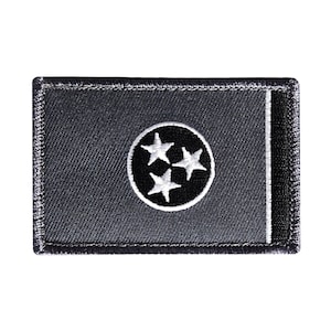 May include: A gray fabric patch with a white embroidered circle containing three white stars on a black background. The patch has a black border.