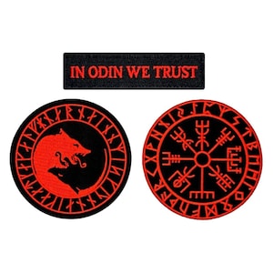 May include: Three embroidered patches with a black background and red stitching. The top patch reads "In Odin We Trust". The left patch features a wolf howling at the moon with runes around the edge. The right patch features a compass with runes around the edge.