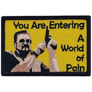 May include: A yellow embroidered patch with a black border. The patch features a cartoon image of a man holding a gun and the text "You Are Entering A World of Pain".