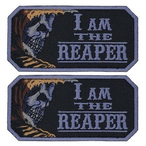 May include: Two black embroidered patches with a white skull and the text "I AM THE REAPER" in white and purple lettering.