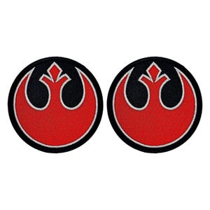 May include: Two red, white, and black embroidered iron-on patches featuring the Rebel Alliance symbol from Star Wars.