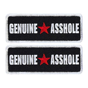 May include: Two black rectangular patches with white stitching around the edges. Each patch has white text that reads "GENUINE ASSHOLE" with a red star between the words.