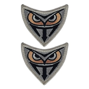 May include: Two gray triangle-shaped patches with a black owl design. The owl has orange eyes and a black beak. The patches have a gray border.