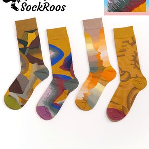 May include: Four pairs of crew socks featuring distinct patterns in shades of mustard yellow, brown, blue, orange, and purple. The first sock has a geometric block design, the second has abstract blue shapes, the third shows layered silhouettes, and the fourth has a textured wave pattern.