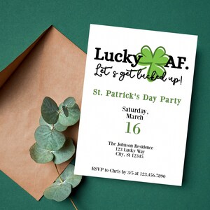 Könnte beinhalten: Eine weiße Einladungskarte mit einem grünen Kleeblatt-Motiv und dem Text "Lucky AF. Let's get bucked up!" für eine St. Patrick's Day Party am Samstag, den 16. März. Die Einladung enthält die Adresse der Party und einen RSVP-Kontakt.