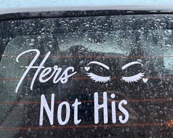 May include: White vinyl sticker on a car window that reads "Hers Not His" with a pair of eyelashes and hearts on either side of the text.