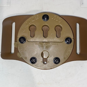 May include: A tan leather belt with a brown plastic holster attachment. The holster has a rotating mechanism with multiple mounting positions. The text "EZ-CLIP" and "PAT. PEND." are visible on the holster.