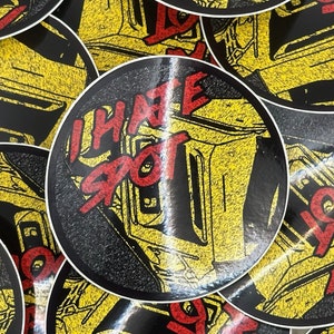 May include: A set of round stickers with a black background and yellow and red text. The text on the stickers reads "I hate spot" and "I love spot".