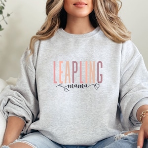 May include: A gray sweatshirt with the text "LEAPLING mama" in pink, orange, and brown lettering with a floral design.