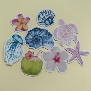 May include: A set of nine stickers featuring various tropical and ocean-themed designs. The stickers include a pink and white hibiscus flower, a blue and white seashell, a pink and white turtle, a blue and white jellyfish, a blue and white nautilus shell, a pink starfish, a green coconut with a pink flower and a straw, and a pink and white frangipani flower.