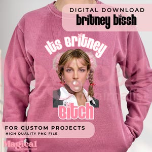 Può includere: Una felpa a maniche lunghe color rosa polvere con la grafica di una persona con codini biondi che soffia una bolla di gomma da masticare rosa. Il testo "its britney" è sopra l'immagine e "bitch" sotto, con "DIGITAL DOWNLOAD britney bissh" in alto.