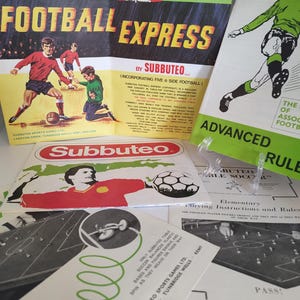 May include: A vintage Subbuteo Football Express game box with a red, white, and blue design. The box features a cartoon image of a man in a red suit and a top hat. The text on the box reads "Football Express by Subbuteo (Incorporating Five-a-Side Football)".