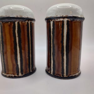 May include: A set of two brown and white striped ceramic salt and pepper shakers.
