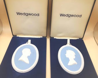 May include: Two Wedgwood blue and white porcelain cameo ornaments in their original boxes. The ornaments feature a white silhouette of a man and a woman on a light blue background.
