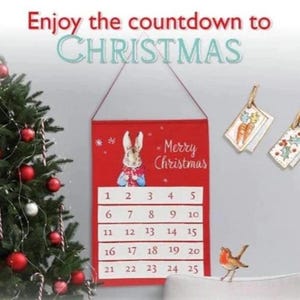 Puede incluir: Un calendario de adviento rojo con un diseño de Peter Rabbit, numerado del 1 al 25. Cuelga junto a un árbol de Navidad decorado con adornos rojos y plateados. El texto "Enjoy the countdown to CHRISTMAS" está en la parte superior.