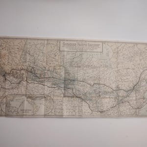 Op de afbeelding: Een antieke kaart van de Canadian Pacific Railway, met gedetailleerde geografische informatie en spoorlijnen. De kaart is gevouwen en gedrukt in tinten beige en grijs, met tekst bovenaan. Afmetingen in cm.