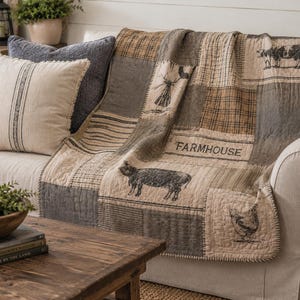 May include: A patchwork quilt featuring a neutral color palette of beige, tan, and charcoal gray. The quilt displays various printed illustrations including a cow, a pig, a chicken, and a windmill, with the word FARMHOUSE printed in black text.