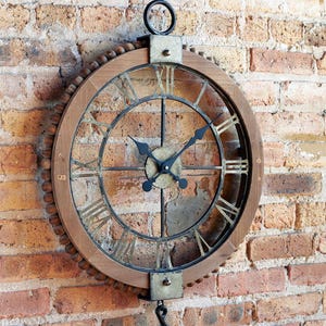 May include: A round wall clock with a wooden frame and metal accents. The clock features Roman numerals and black clock hands. The clock is hanging on a brick wall. The clock's diameter is approximately 20 inches.
