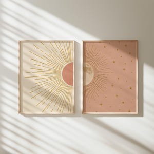 Sunlight casts diagonal shadows across two framed celestial prints mounted on a pale wall.
