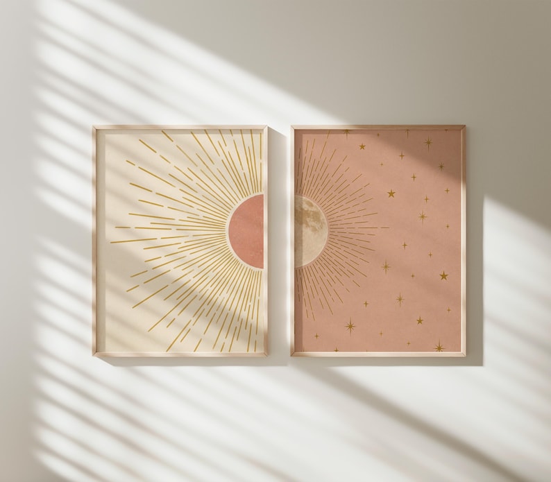 Sunlight casts diagonal shadows across two framed celestial prints mounted on a pale wall.