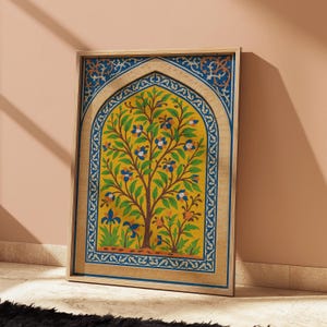 Puede incluir: Obra de arte enmarcada que presenta un árbol estilizado con hojas verdes y flores azules sobre un fondo amarillo. El marco de madera tiene un borde decorativo azul y dorado. La obra está apoyada contra una pared color melocotón.