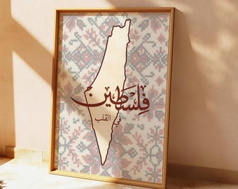 May include: Framed art print featuring a map outline of Palestine in a light tan color, with Arabic calligraphy and a patterned background in red, gray, and white. The wooden frame adds a natural touch to the artwork.