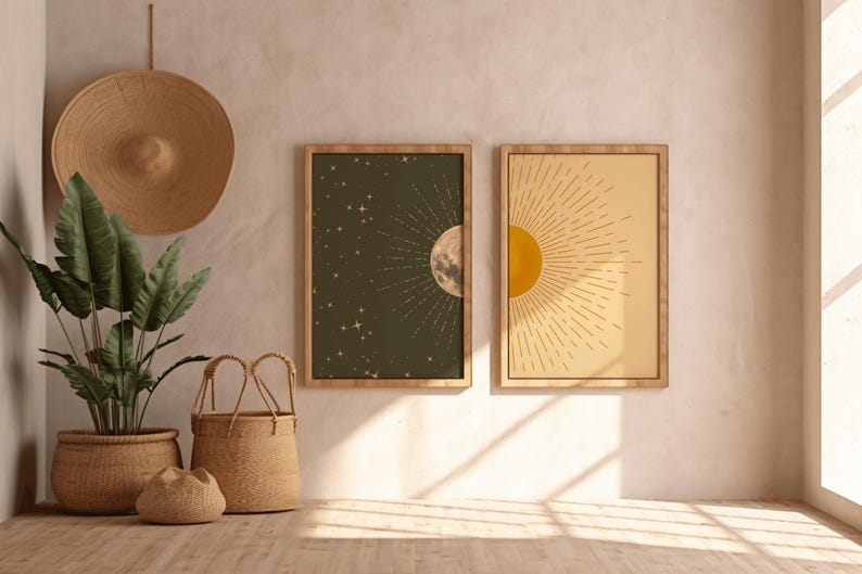 Two framed sun and moon posters mounted on a textured plaster wall in a room with woven baskets, a potted plant, and a straw hat hanging on the left.