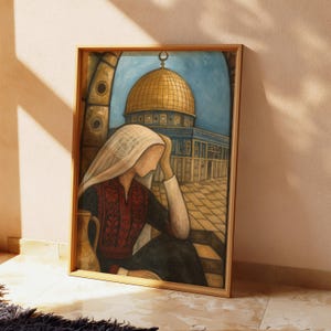 May include: Framed artwork showing a woman in traditional Palestinian dress, looking at the Dome of the Rock. The painting features a gold dome, blue sky, and a warm colour palette. The frame is made of light-coloured wood.