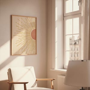 A single framed sun print hangs on a light wall next to a large window and a white armchair.