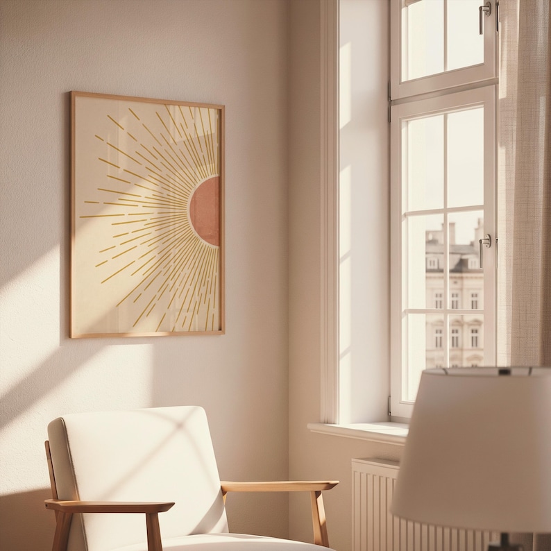 A single framed sun print hangs on a light wall next to a large window and a white armchair.